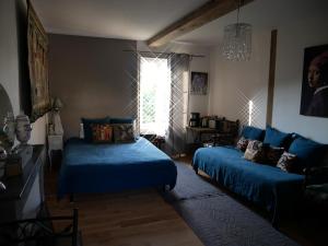 1 Schlafzimmer mit 2 blauen Betten und einem Fenster in der Unterkunft Chateau de Sainte Colombe Sur Gand in Sainte-Colombe-sur-Gand