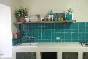 uma cozinha com um lavatório e uma parede de azulejos verdes em Casetta Nonna Augusta (Spello 9 km-Assisi 12 km) em Spello