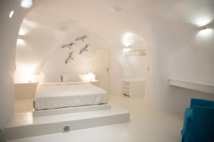 una camera bianca con un letto in una stanza di Aleria Luxury Cave Santorini a Éxo Goniá