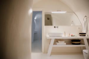 un bagno bianco con lavandino e specchio di Aleria Luxury Cave Santorini a Éxo Goniá