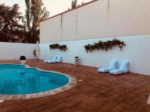 a patio with a swimming pool next to a white wall at Emperatriz III in Santa Marta de Tormes