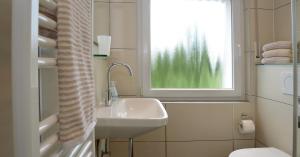 baño blanco con lavabo y ventana en Haus Sigge Ferienwohnungen, en Bad Sassendorf