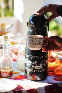 a person holding a cup in front of a bottle at Doce Lar Hospedaria in Lençóis +61 photos