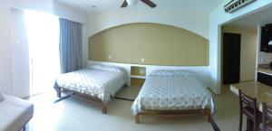 a bedroom with two beds and a mirror at Hotel Bogavante in Barra de Navidad