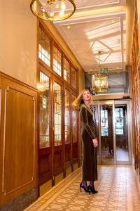 a woman in a black dress standing in a hallway at Hotel Royal in De Panne