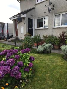 uma casa com flores roxas no quintal em Highfield apartment em Inverness