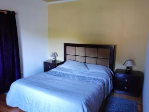 um quarto com uma cama grande e duas mesas de cabeceira em A casa do Tí Mendonça em Lajes das Flores
