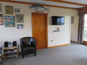Habitación con puerta, silla y TV. en Glendale River View, en Manapouri