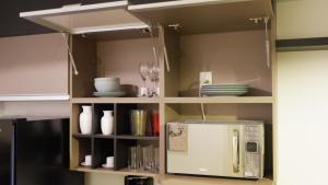 a cupboard with a microwave in a kitchen at Estudio Alto da Boa Vista in Sao Paulo