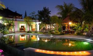una piscina frente a una casa por la noche en HOTEL SEGARA MANDALA en Negara