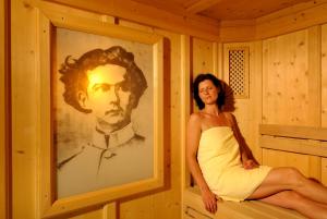 a woman sitting in a sauna next to a picture at Hotel Schlosskrone in Füssen