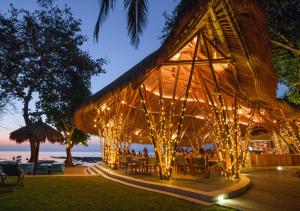a restaurant with lights on the beach at night at Hai Tide Beach Resort in Nusa Lembongan