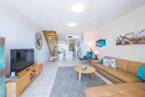 a living room with a couch and a tv at On The Beach Resort Bribie Island in Woorim