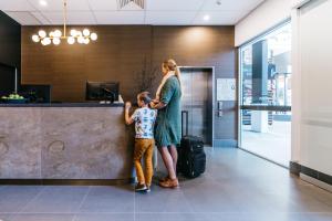 a woman and a child standing next to a counter at Gabba Central Apartments in Brisbane