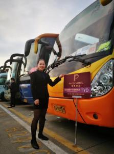 a woman is standing in front of a bus at Paco Hotel Tuanyida Metro Guangzhou -Free ShuttleBus for Canton Fair in Guangzhou