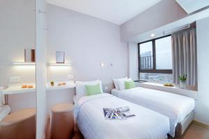 a hotel room with two beds and a window at Hotel Ease Mong Kok in Hong Kong
