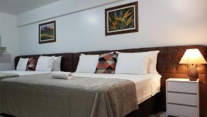um quarto com duas camas e um candeeiro sobre uma mesa em B & A Suites Inn Hotel - Quarto Luxo Palladium em Anápolis