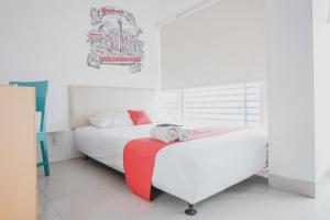 a bedroom with two beds and a red blanket at RedDoorz Plus @ Kapuk Business Park in Jakarta