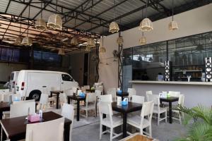 a restaurant with tables and white chairs and a white van at RedDoorz Plus @ Kapuk Business Park in Jakarta