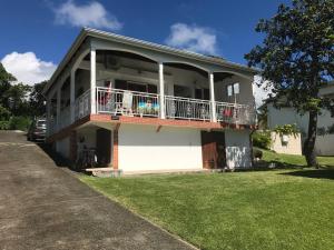 a white house with a balcony and a yard at Le repaire des Caraïbes in Trois-Rivières