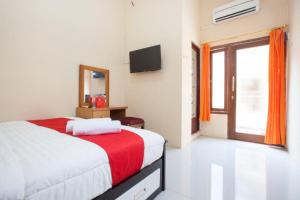 a bedroom with a bed and a television and a window at RedDoorz Syariah near UNTAG Banyuwangi in Banyuwangi