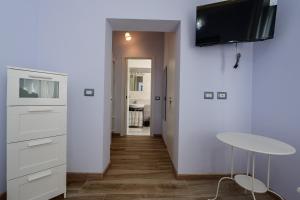 een woonkamer met een tafel en een tv aan de muur bij PATTY'S GUESTHOUSE in Parma