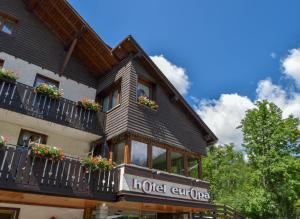 ein Hotelgebäude mit einem Balkon mit Blumen darauf in der Unterkunft Hotel Europa in Madonna di Campiglio