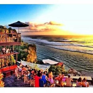a group of people sitting at a bar on the beach at Bali Bobo Hostel in Jimbaran