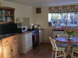 a kitchen with a table and a microwave and a table with chairs at Freshwater Barn in Benenden