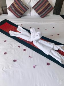 a bed with red rose petals on it with towels on it at Jasmine Vangvieng Hotel in Vang Vieng