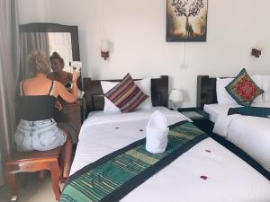 a woman in a room with two beds at Jasmine Vangvieng Hotel in Vang Vieng