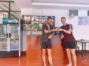 two men standing in front of a bar at Jasmine Vangvieng Hotel in Vang Vieng