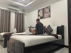 a man sitting on a bed in a room at Jasmine Vangvieng Hotel in Vang Vieng