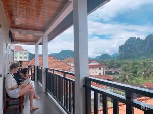 a woman sitting on a balcony looking out at the mountains at Jasmine Vangvieng Hotel in Vang Vieng
