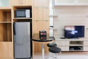 a kitchen with a table and a refrigerator and a tv at Brand New Cozy Studio at Scientia Apartment By Travelio in Tangerang