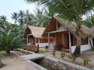 a house with a thatched roof and a palm tree at Bungalow in Karimunjawa