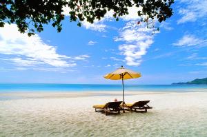 two chairs and an umbrella on a beach at Buri Rasa Village Samui in Chaweng