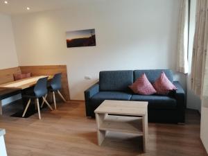 a living room with a blue couch and a table at Haus Scheiber in Umhausen