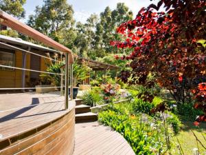 a garden with red flowers and a wooden walkway at Kingfisher in Margaret River Town