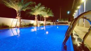 a blue swimming pool with palm trees at night at Pleasant Chiangmai in Chiang Mai