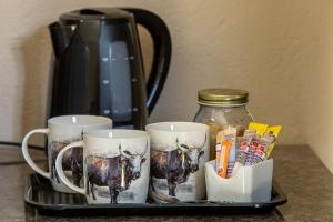 a tray with three coffee mugs with a cow on it at Kiyala Guest Farm in Nelspruit +10 photos