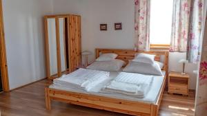 a bedroom with a wooden bed with white sheets and pillows at Ebner Pince - Panzió in Turbékpuszta