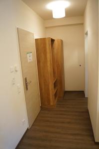 un corridoio vuoto con una porta e una camera con pavimenti in legno di Braumeister Döbler - Ferienwohnungen a Bad Windsheim