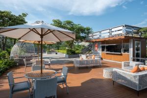 a patio with a table with an umbrella and chairs at HARRIS Resort Barelang Batam in Sagulung