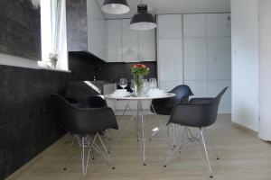 a dining room with a white table and black chairs at Impresja 42 Apartament z garażem in Kołobrzeg