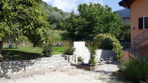 un jardín con una pared de piedra y árboles y un edificio en Casa Gina Garden and view by Gardadomusmea en Tremosine Sul Garda