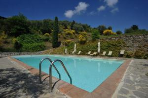 een zwembad met stoelen en een stenen muur bij La Casa nel Castello di Gaiche in Piegaro