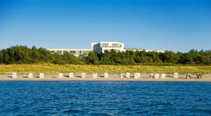 einen Strand mit Stühlen und Gebäuden im Hintergrund in der Unterkunft Strandhotel Fischland in Dierhagen