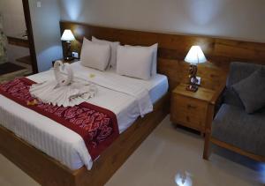 a hotel room with a bed and a chair at Swan Inn in Ubud