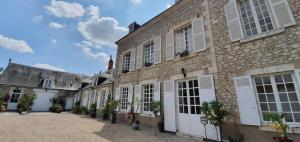 an old brick building with white doors and windows at La Folie Hubert in Meung-sur-Loire